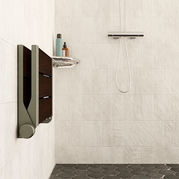A SerenaSeat folded against a white tile shower wall.