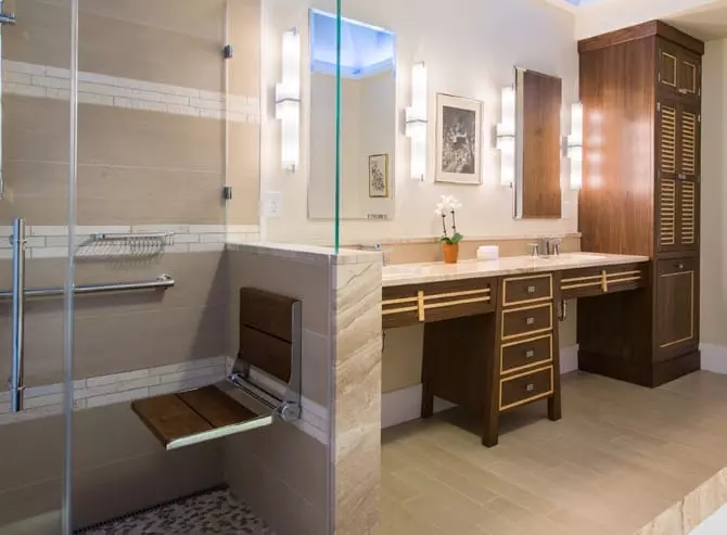 A wide angle image of a walk in shower and bathroom sink. With A serenaseat placed in the foreground