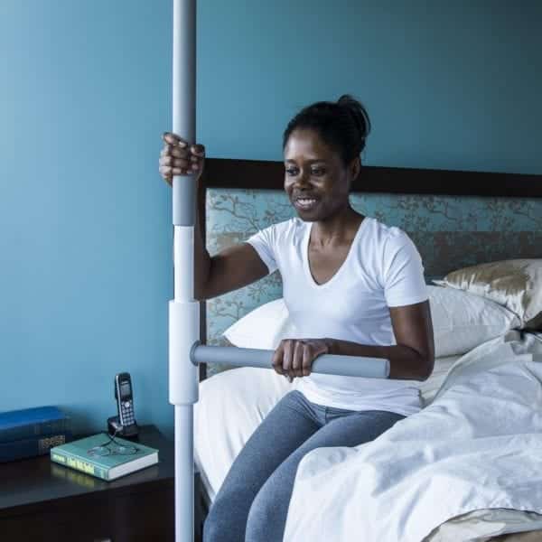 Woman using the SuperPole with Super to help her sit up and stand up from the bed