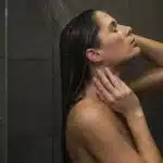 The Invisia Accent Bar installed in a luxurious shower where a woman is rinsing her hair.