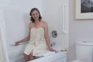 A woman in a Towel holding a shower grab bar