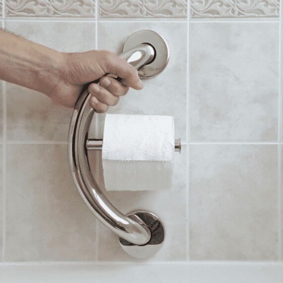 Hand grabbing a toilet paper holder grab bar.