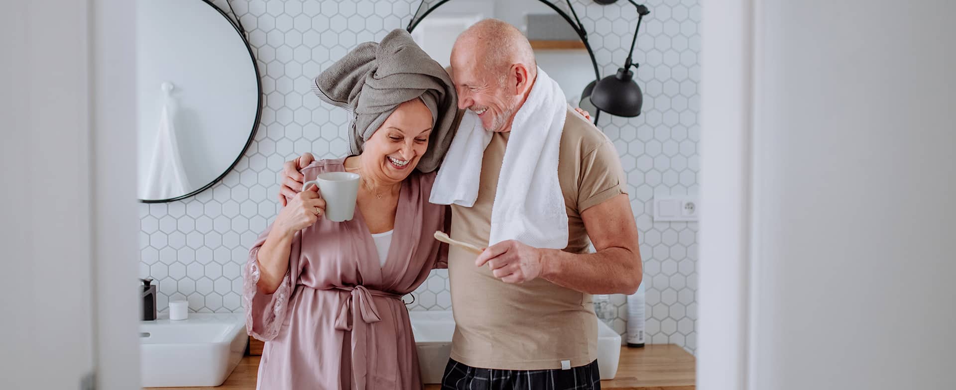 A senior couple hugging while getting ready in a renovated bathroom.