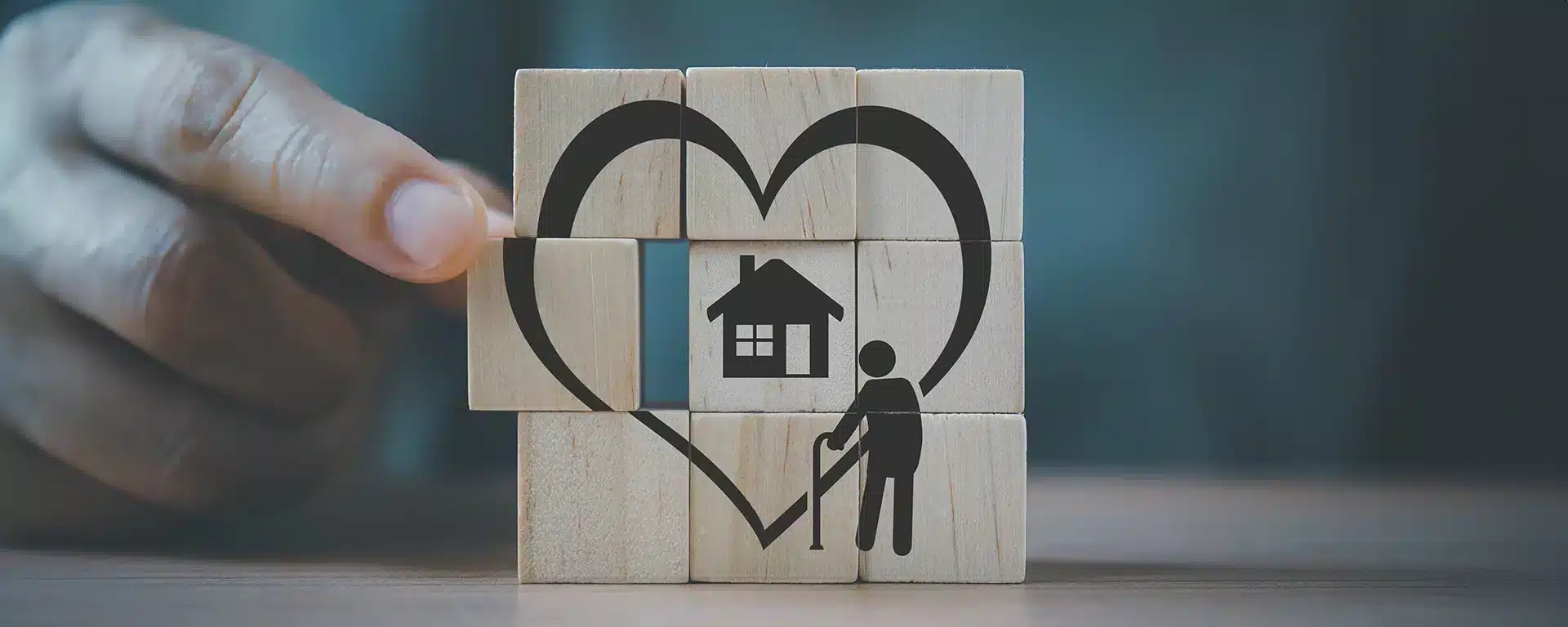 A puzzle made of 9 stacked blocks completing an illustration of an elderly person with a home and a heart around it.