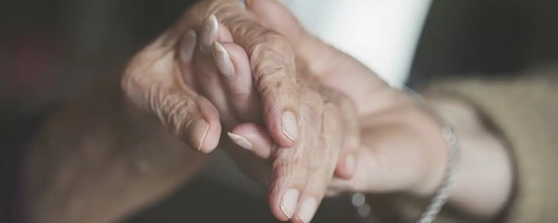 A close-up of two seniors holding hands.